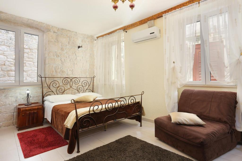 特罗吉尔Apartments by the sea Trogir - 19575的一间卧室配有一张床、一把椅子和窗户。