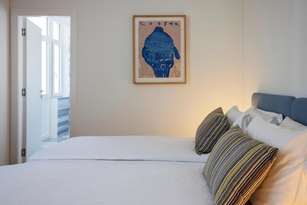 洛迦诺Villa Rossella的一张带枕头的白色床和墙上的照片