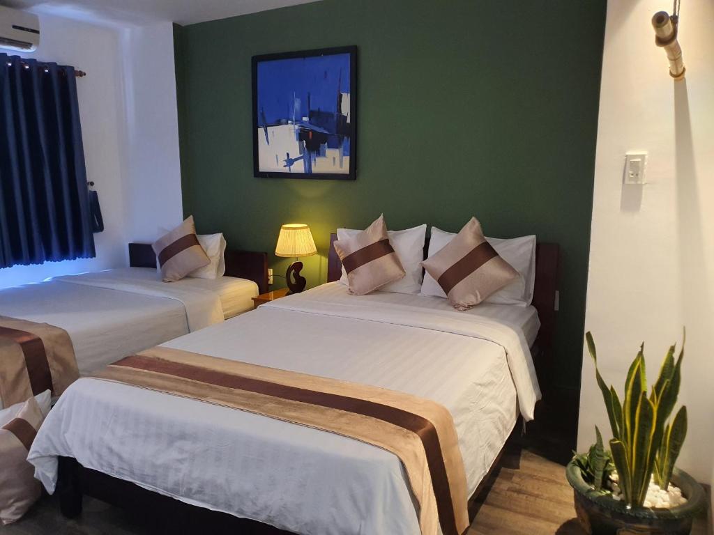 胡志明市Tony SaiGon Hotel的绿墙客房内的两张床