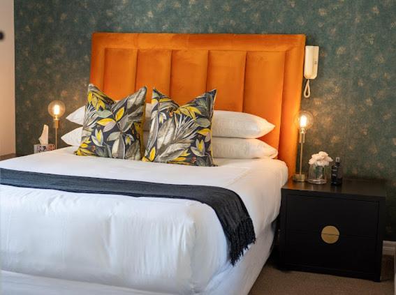 约翰内斯堡Nal'enzo Luxe Stays的一间卧室配有一张带橙色床头板和枕头的床。