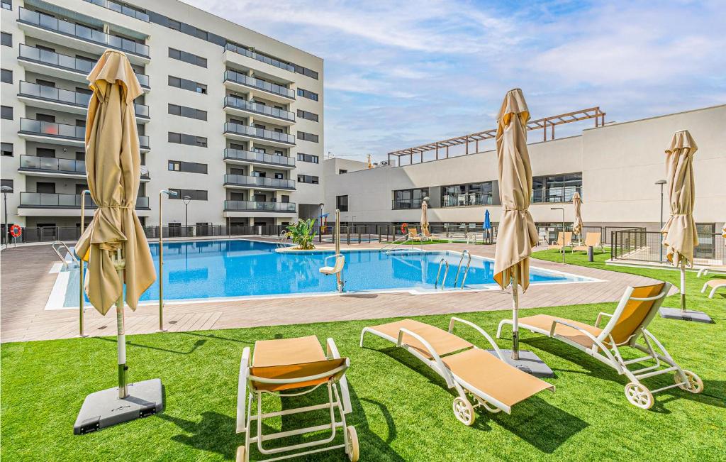 塞维利亚Beautiful Apartment In Sevilla With Wifi的大楼前的带椅子和遮阳伞的游泳池