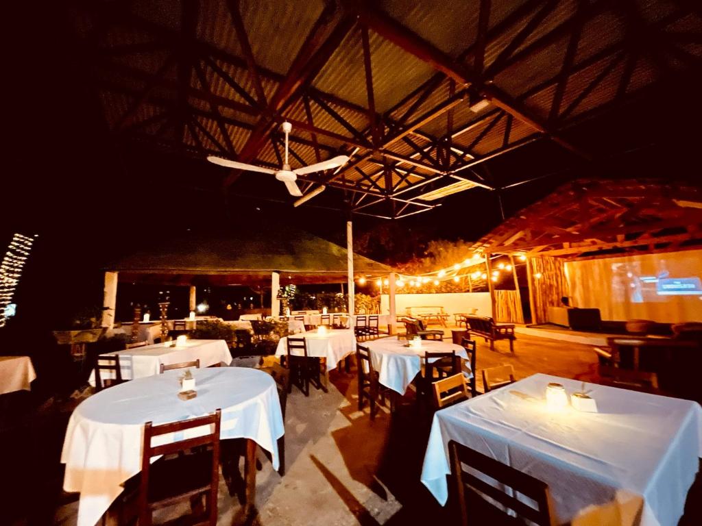 图利亚拉CHEZ ALAIN的餐厅设有白色的桌椅和天花板