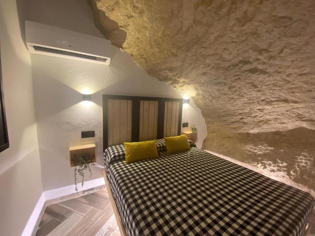 塞特尼尔Casa Rural Bajo la Alcazaba的洞穴壁房间里一张床位