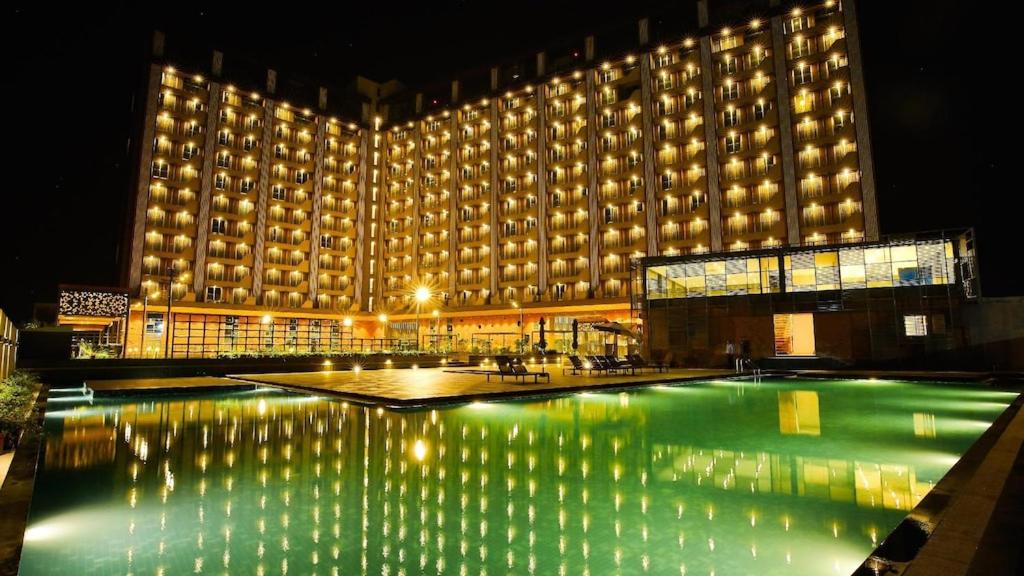 苏拉特Weekend Address managed by Global Hospitality的一座大型建筑,晚上设有游泳池