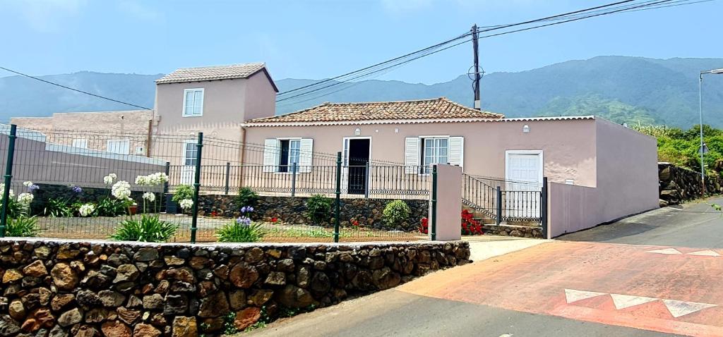 上布雷尼亚Casa Los Agapantos的粉红色的房子,有栅栏和石墙