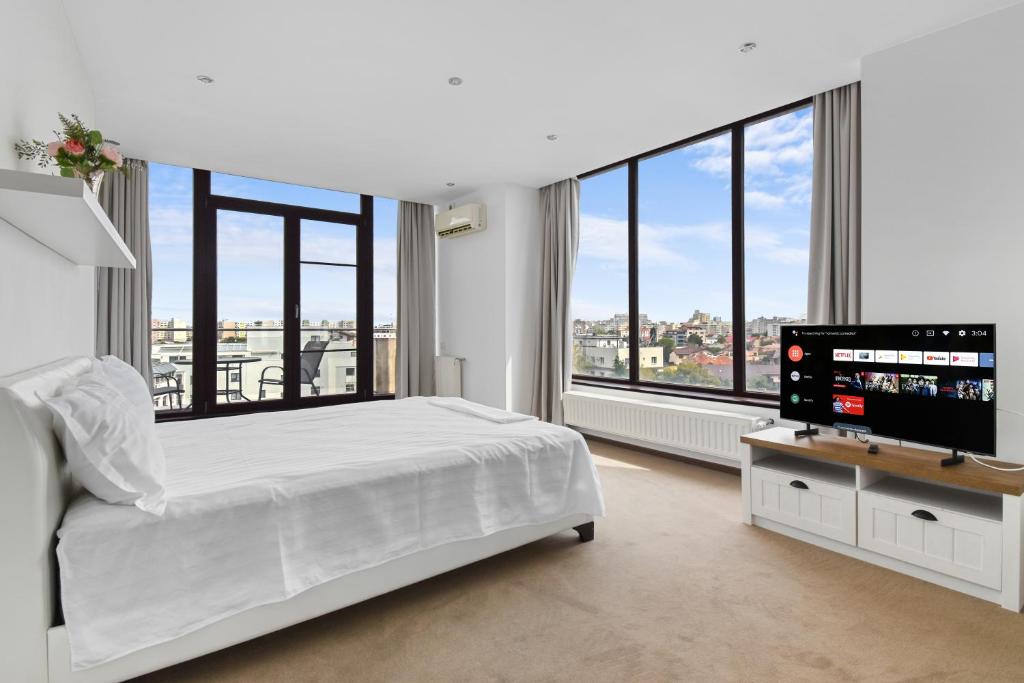 布加勒斯特One88 Apartments的白色卧室配有床和平面电视