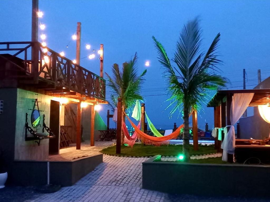 南圣弗朗西斯科Pousada Mar e Paz的一个带吊床的游乐场,晚上还种植了棕榈树