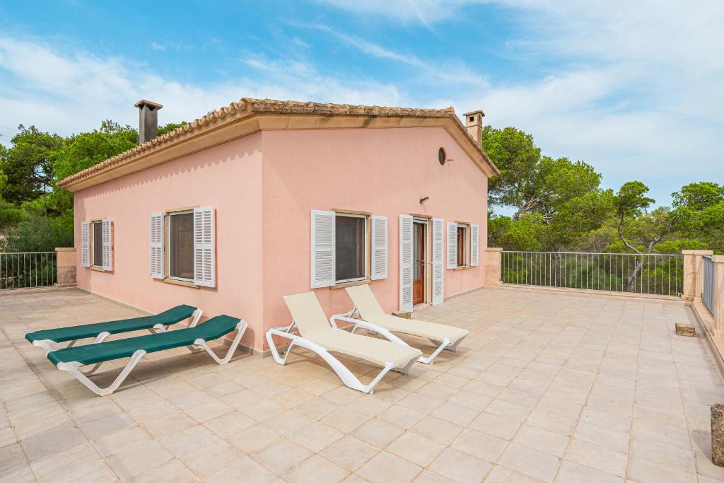 卡拉桑塔尼Villa Rosa的粉红色的房子,配有两把椅子和天井上的长凳