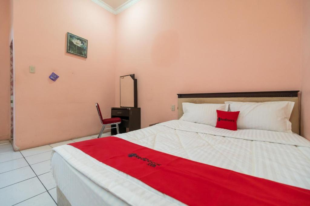 SiborongborongRedDoorz near Silangit International Airport的一间卧室配有一张床铺,床上铺有红色毯子
