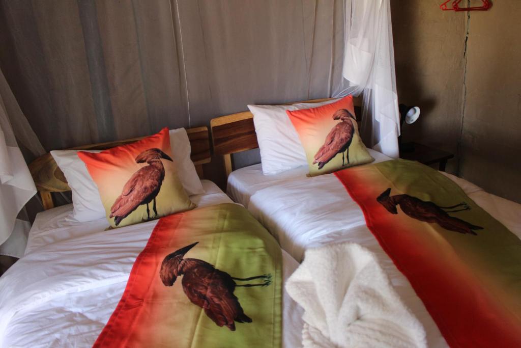 KongolaMukolo Cabins & Camping的卧室内的两张床,枕头上有鸟儿