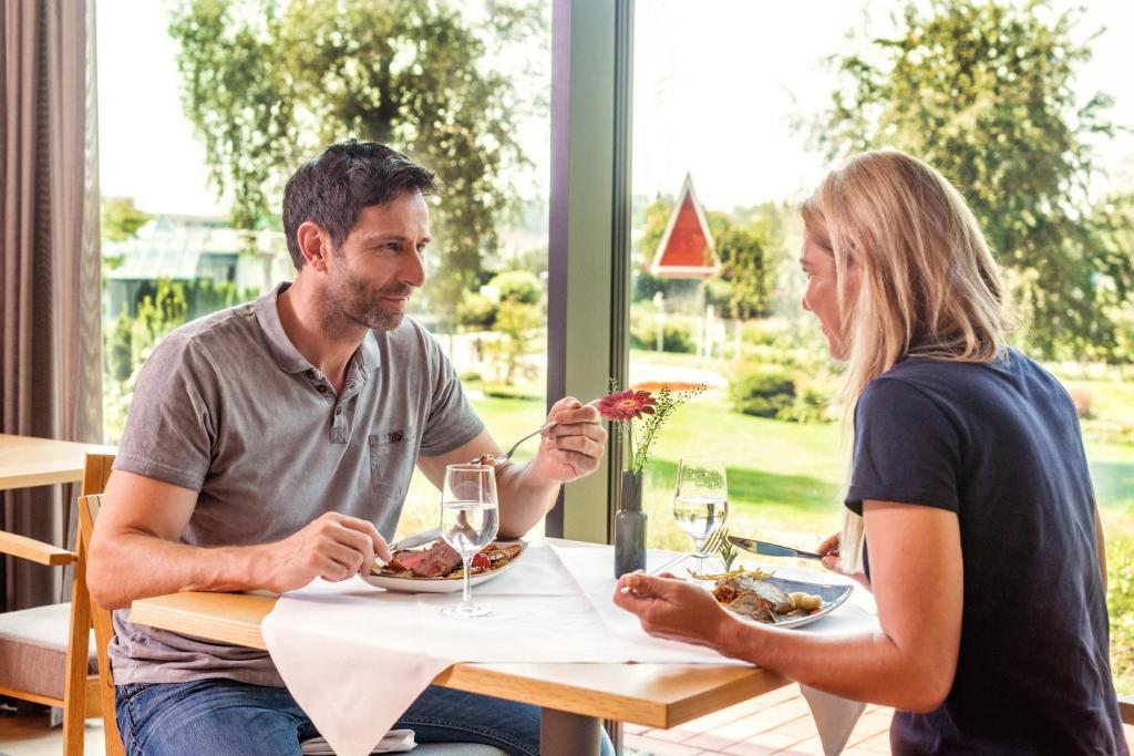 巴特布豪Thermenhotel Gesundheits-Bad Buchau的坐在餐桌旁吃食物的男人和女人