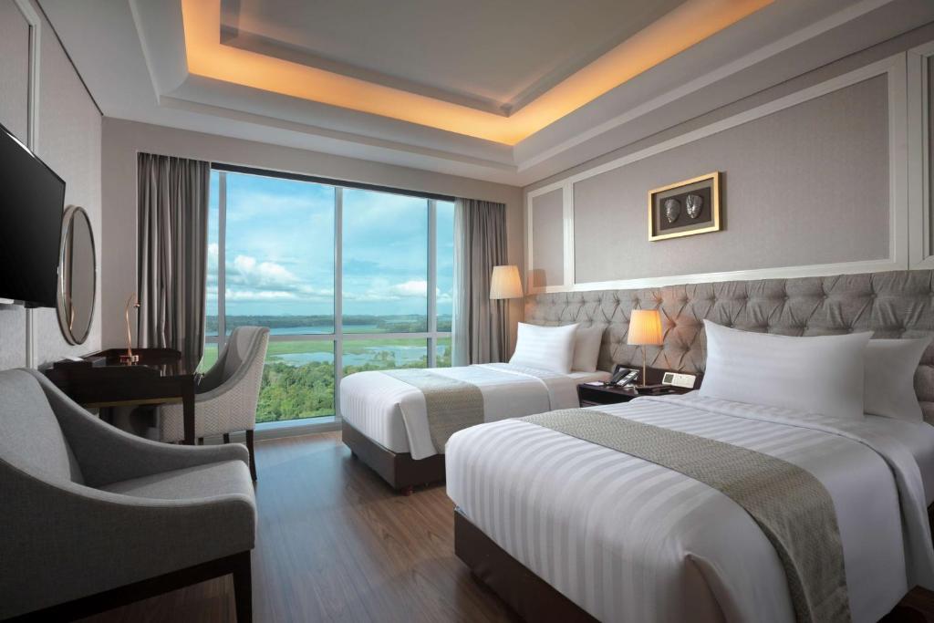 巴淡岛中心潘比尔贝斯特韦斯特优质酒店的酒店客房设有两张床、一张书桌和一个窗户。