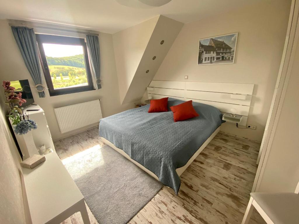 艾森纳赫Ferienhaus Auenblick DELUXE的一间卧室配有一张带两个红色枕头的床
