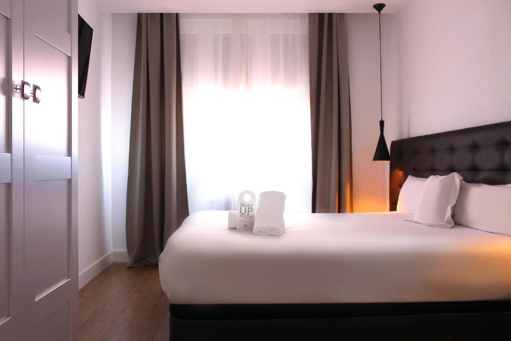 马德里马德里乌胡套房旅馆的卧室配有一张大白色床和窗户