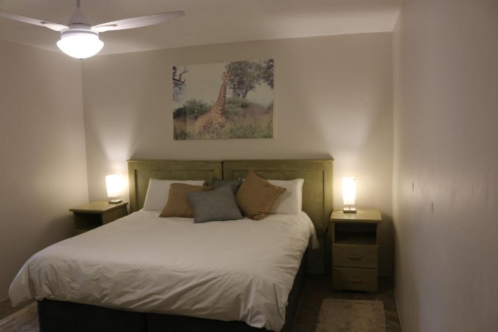 SimunyeLivivane Guest House的一间卧室配有一张带2个床头柜和2盏灯的床。