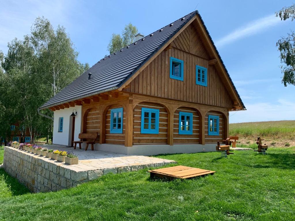 DubáRoubenka Kokořínsko的大型木制房屋,在田野上设有蓝色窗户