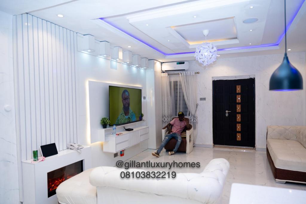 贝宁城Gillant Luxury Homes的一名男子坐在客厅的沙发上