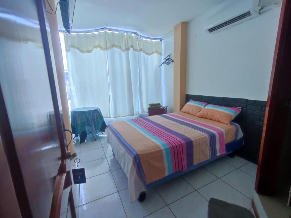 曼塔Hostal Venecia -Tu casa en Manta.的一间卧室配有一张带条纹毯子的床和窗户