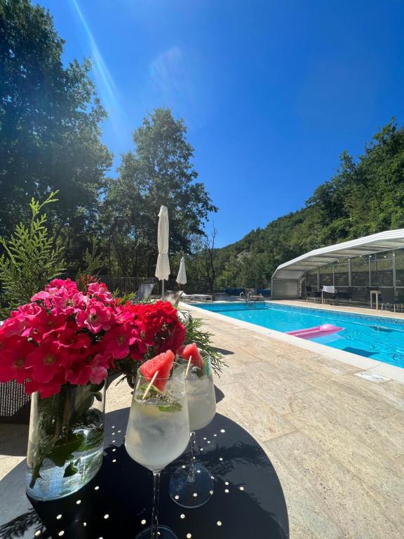 Villa MinozzoLe Boccede Country House B&B的游泳池旁的桌子,带两杯和鲜花
