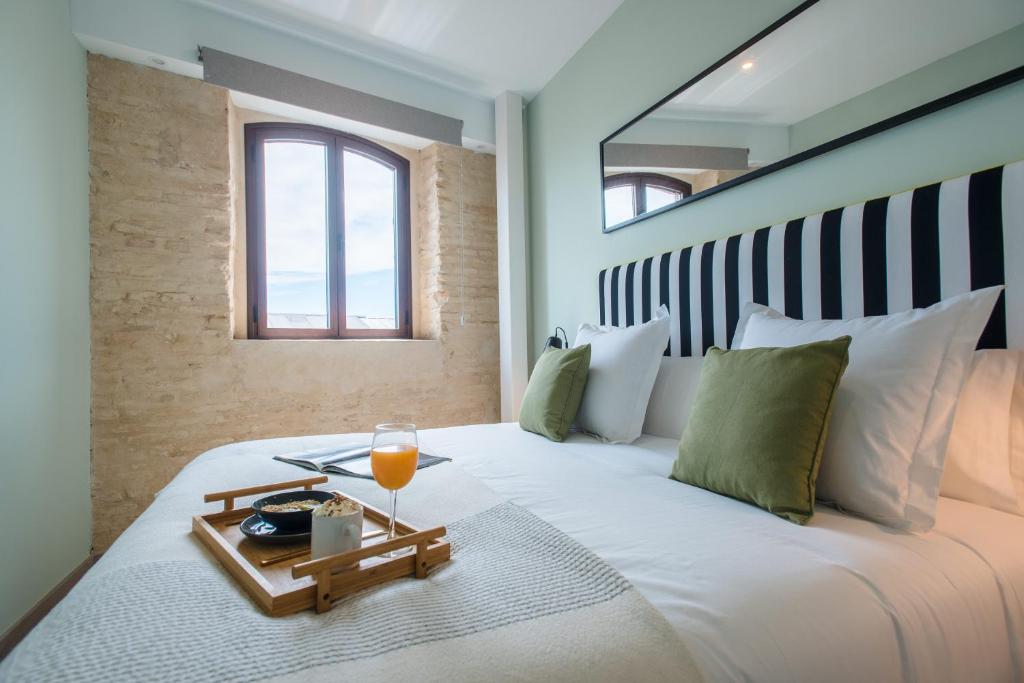 塞维利亚Sercotel Sevilla Guadalquivir Suites的一间卧室配有一张床,上面放着一个食物托盘