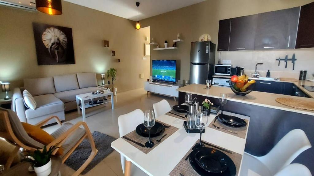 拉纳卡Paramount Gardens Resorts C202的厨房以及带沙发和桌子的客厅。