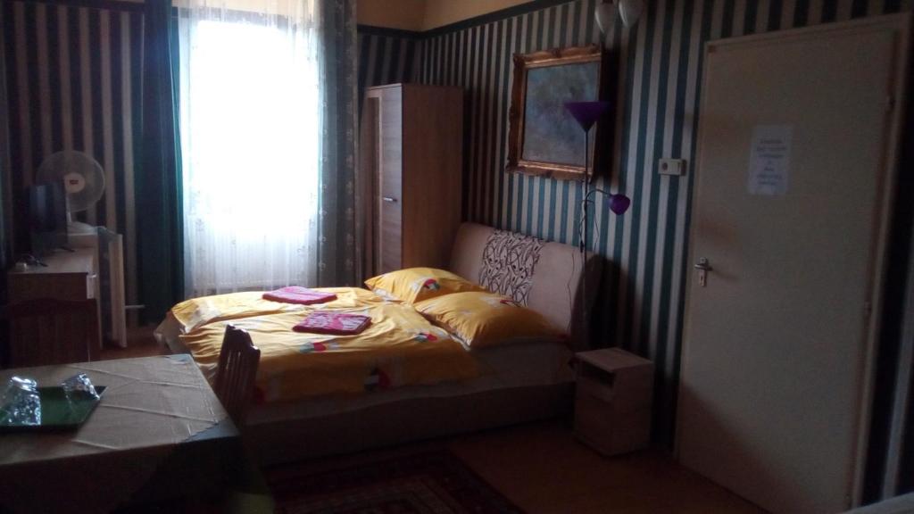 尼赖吉哈佐Jocó Panzió的一间卧室配有一张带黄色床单的床和一扇窗户。