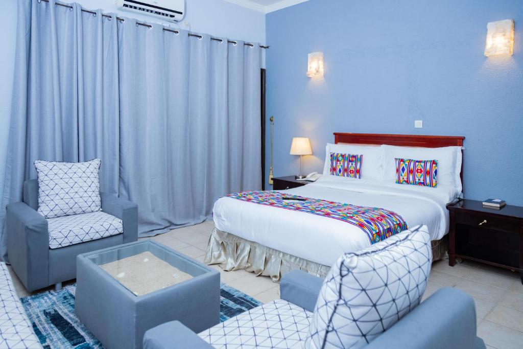 利伯维尔Hotel Hibiscus Blvd Triomphal的配有一张床和一把椅子的酒店客房