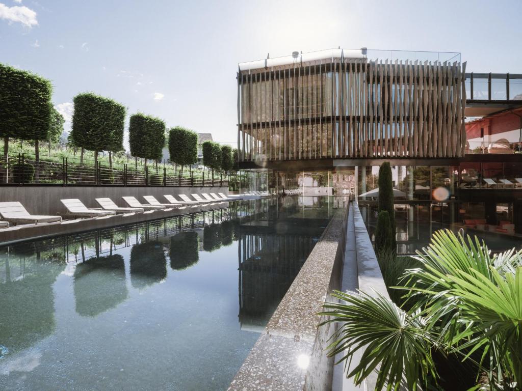 纳图尔诺Lindenhof Pure Luxury & Spa DolceVita Resort的一个带躺椅的水池和一座建筑
