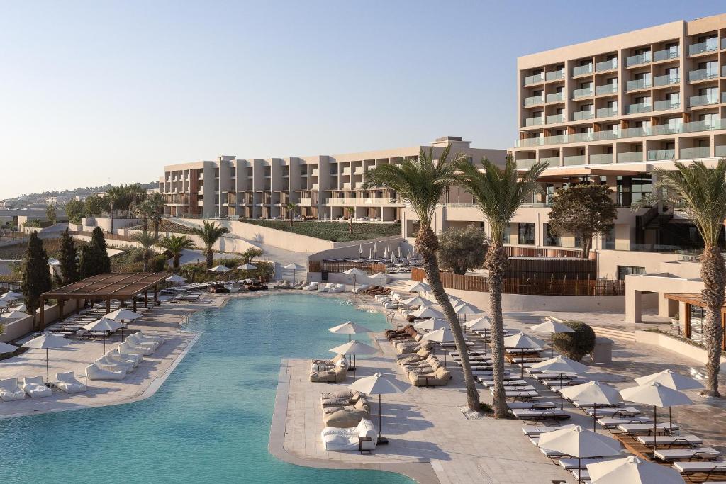 罗德岛卡利地亚Helea Lifestyle Beach Resort的一个带椅子和遮阳伞的游泳池的度假酒店