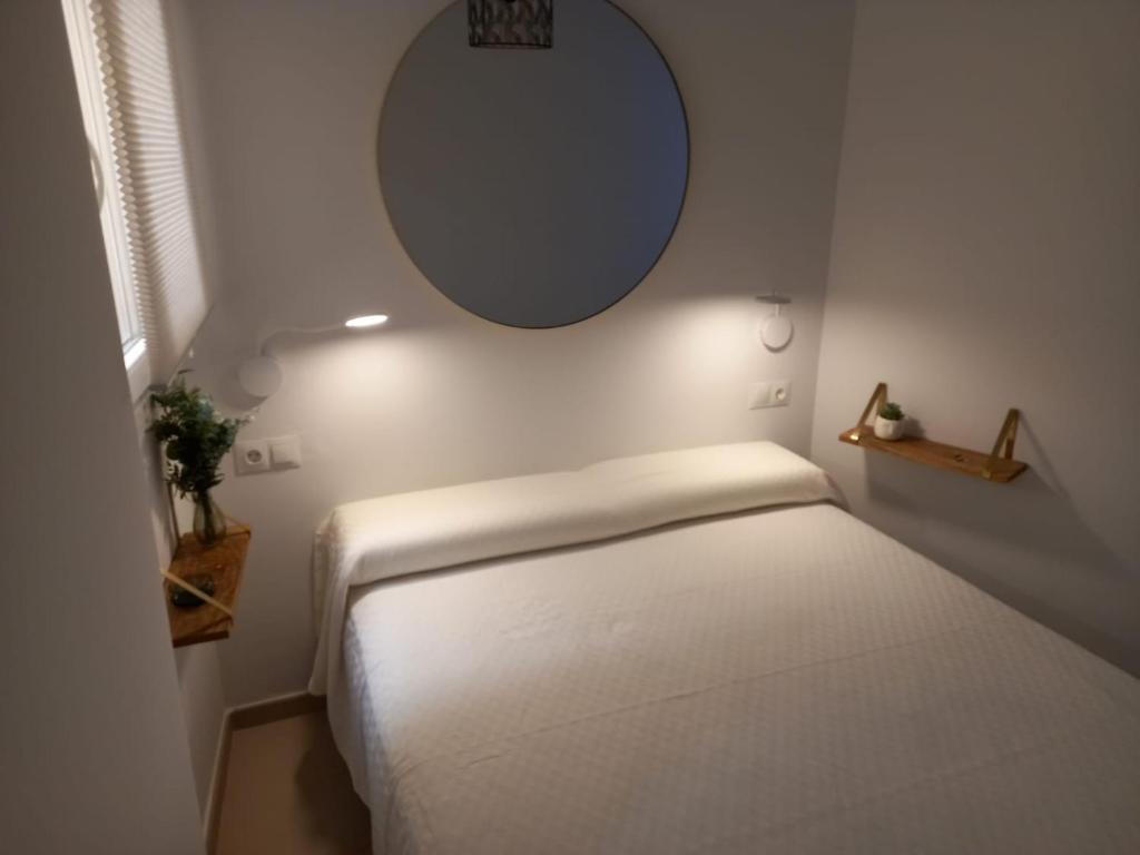 马拉加Frailes的一间小卧室,配有白色的床和镜子