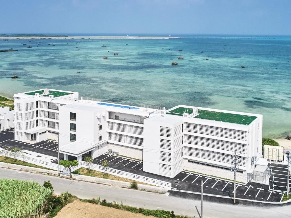 宫古岛Watermark Hotel & Resorts Okinawa Miyakojima的靠近大海的白色建筑的空中景观