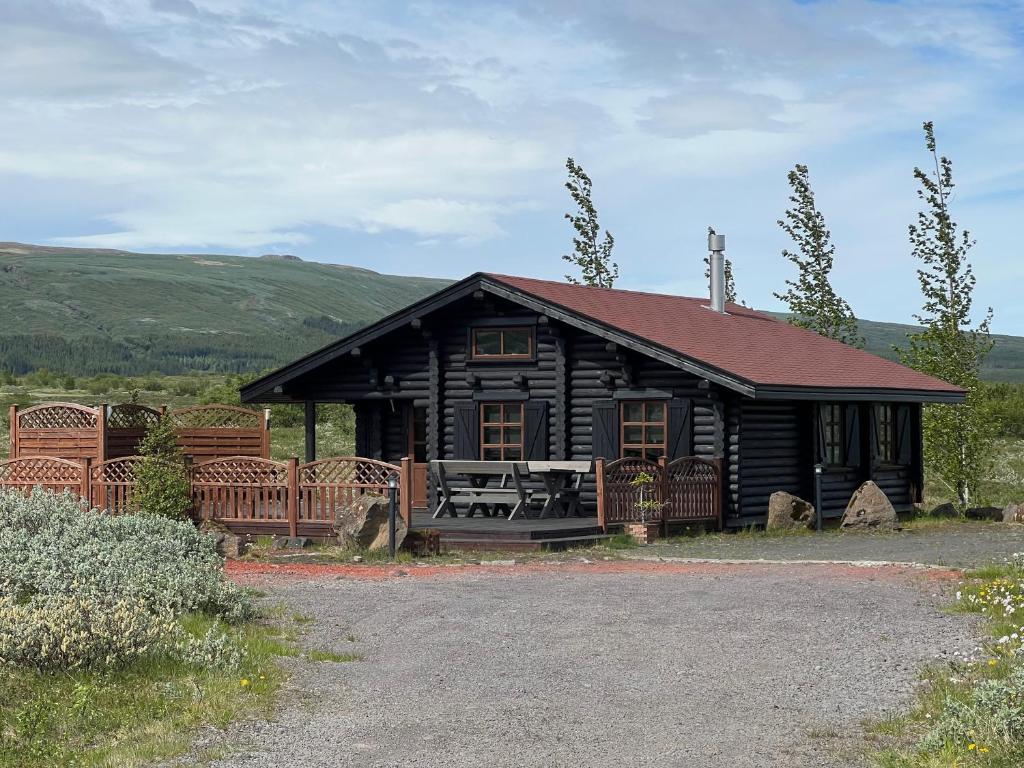 BlaskogabyggoCosy cabin with amazing view on the Geysir的小木屋前面设有桌子和长凳