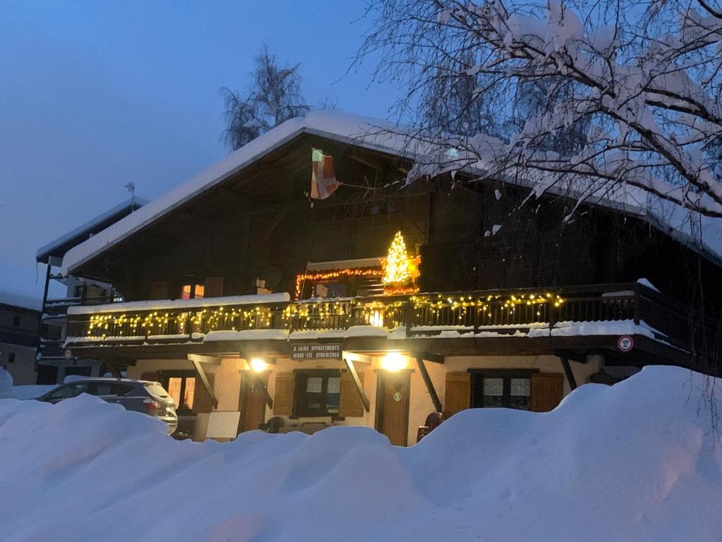 雷塞兹APPARTEMENT VUE SUR LES PISTES Aux SAISIES 4的雪覆盖着的房屋,上面有圣诞树