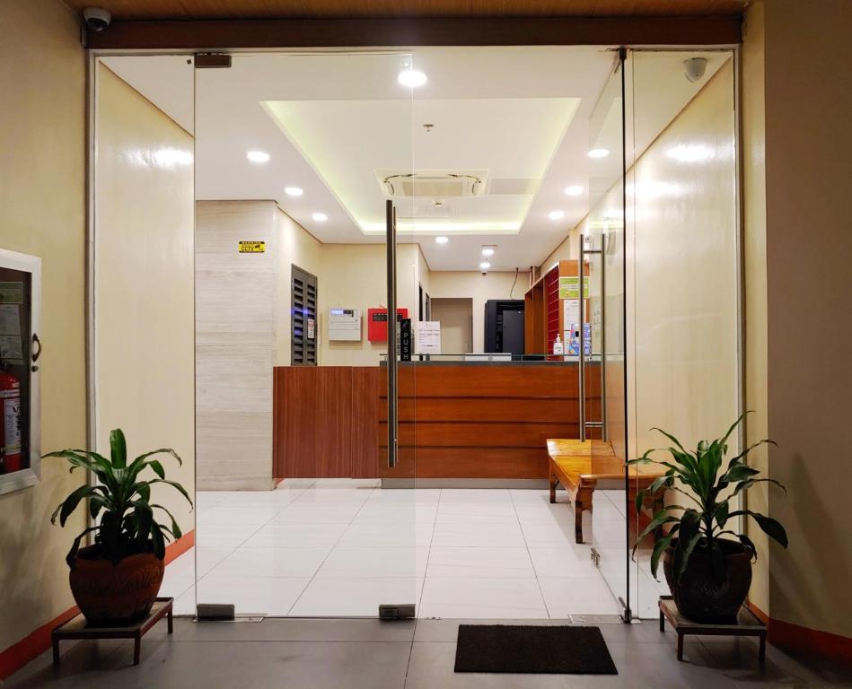 马尼拉Kaizen Suites的办公室大厅,设有玻璃门和盆栽植物