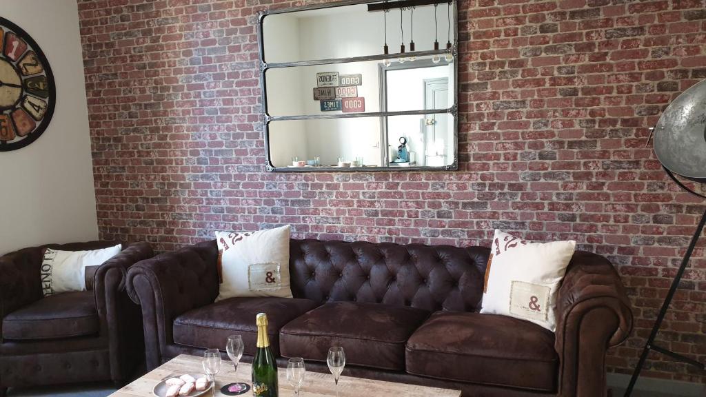 埃佩尔奈Le Loft Vintage Epernay avec Netflix, Vélos, Parking gratuit的客厅配有棕色皮沙发和砖墙