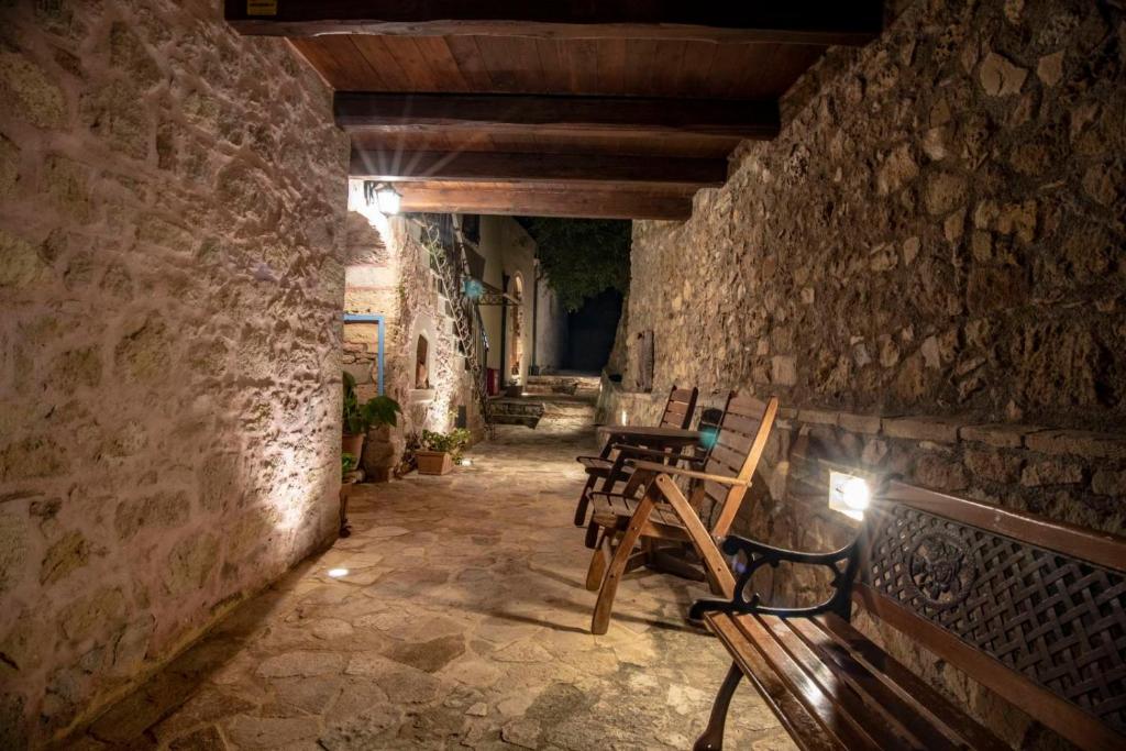 凯里瓦尼STAMATOGIANNIS Traditional Apartments的石头走廊上的一组木椅