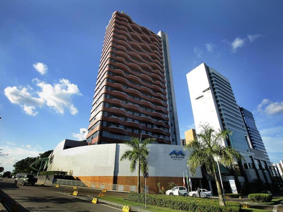 马瑙斯Millenium Hotel Flat的一座高大的建筑,旁边是棕榈树建筑