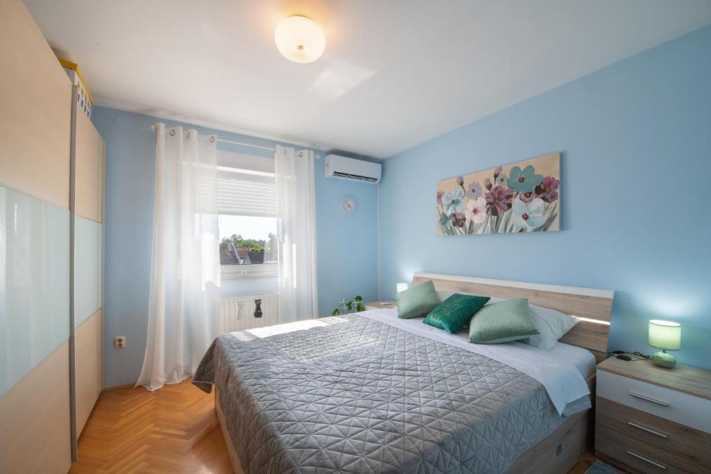 奥西耶克Apartman Silvija的一间卧室配有一张蓝色墙壁的床和一扇窗户