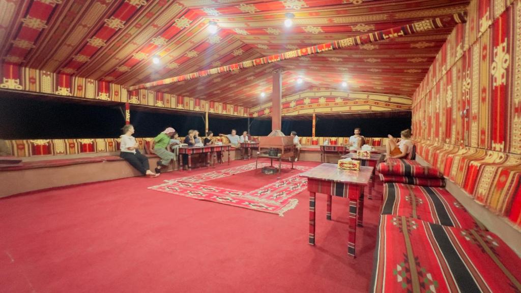 瓦迪拉姆Bedouin host camp& with tour的一间大房间,里面的人坐在桌子上