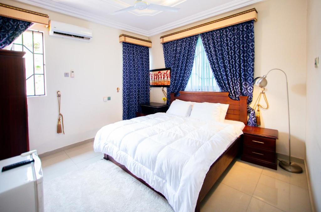 OteleAduk Guest House Airport City Accra的一间卧室配有大床和蓝色窗帘