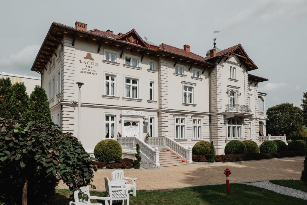Kazimierza Wielka帕拉克拉肯酒店的一座白色的大建筑,前面有两把白色椅子