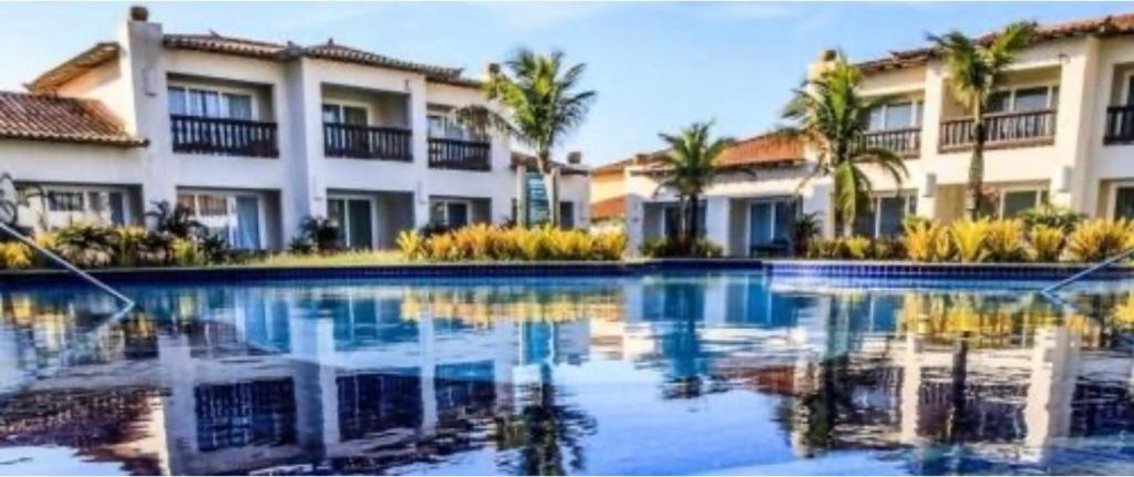 布希奥斯Buzios Beach Resort Super Luxo Residencial 2501 e 2502的棕榈树建筑前的游泳池