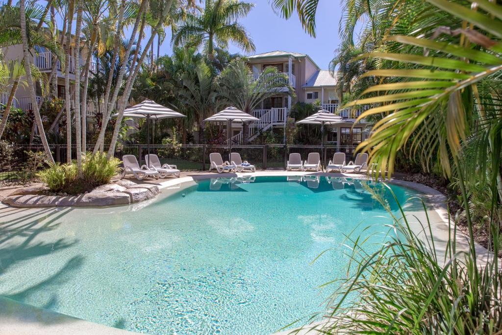 努萨维尔海滩度假酒店的一个带椅子和遮阳伞的游泳池