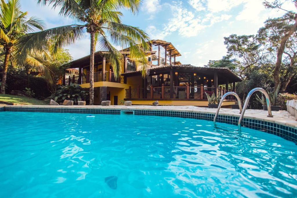 伊利亚贝拉Pousada Canto da Mata Ilhabela的棕榈树屋前的游泳池