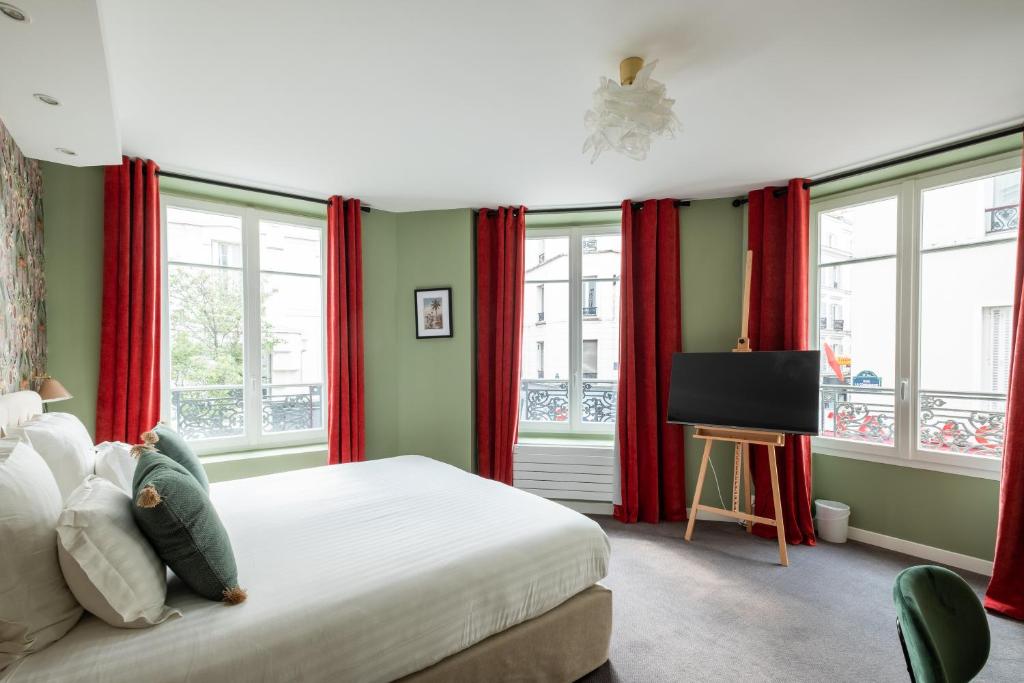 巴黎巴蒂诺勒酒店的一间卧室配有红色窗帘和一张带电视的床