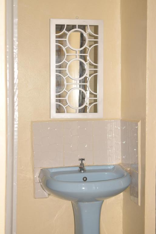 KakamegaBeautiful 1BR with Wi-Fi & secure parking的一间带水槽和彩色玻璃窗的浴室