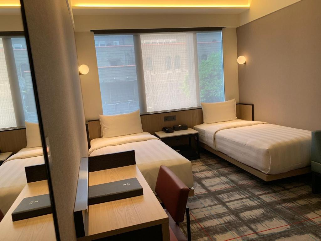 台北德立庄酒店的酒店客房设有两张床和一张桌子。