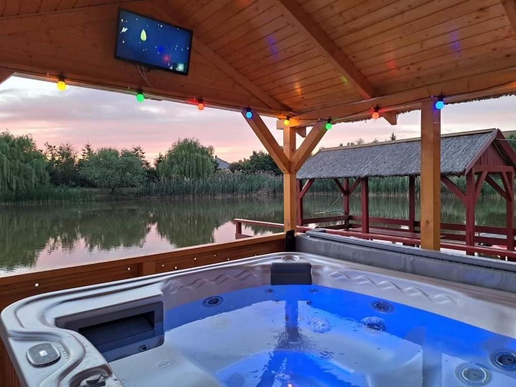 VajdácskaGólya-Tó Vendégház的一个带顶棚的甲板上的热水浴缸,配有电视