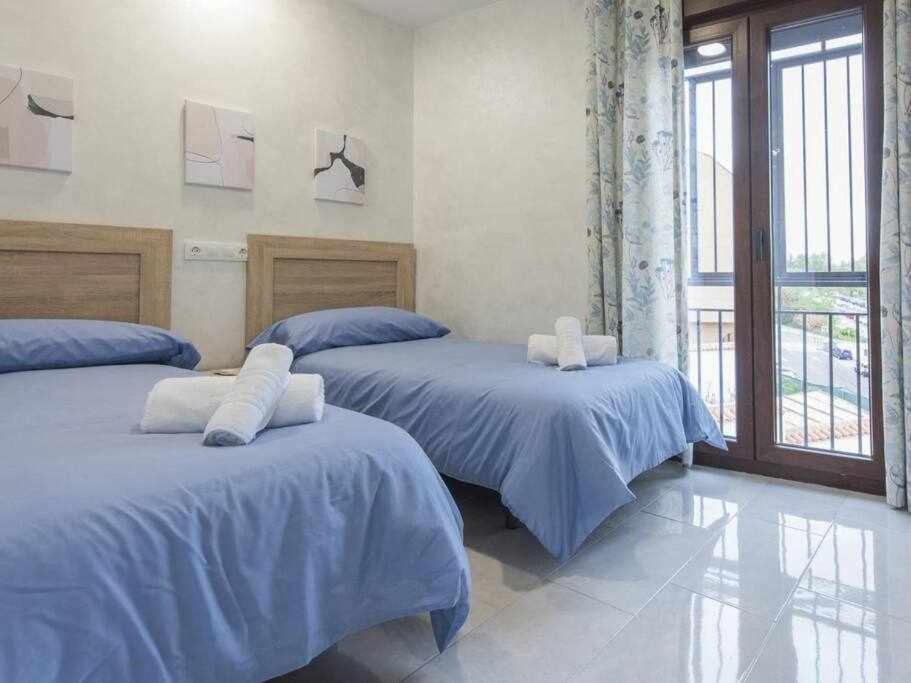 托莱多La casita del caracol by Toledo AP的一间卧室设有两张带蓝色床单的床和窗户。