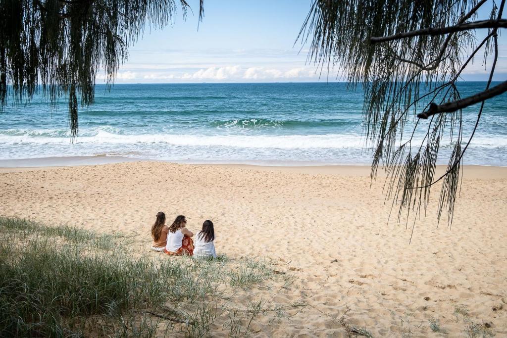 卡伦德拉Coastal Getaway Across From Dicky Beach的三个女孩坐在沙滩上